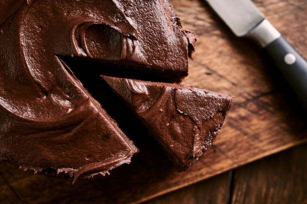 Sliced indulgent Chocolate cake against a rustic aged wooden surface.